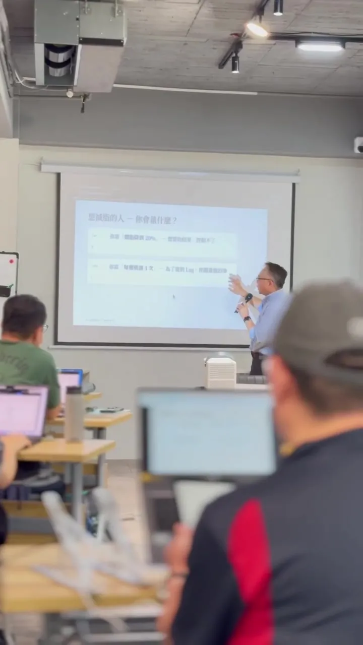 Seen from the back of the room: participants, their laptops, and the projector screen in the distance